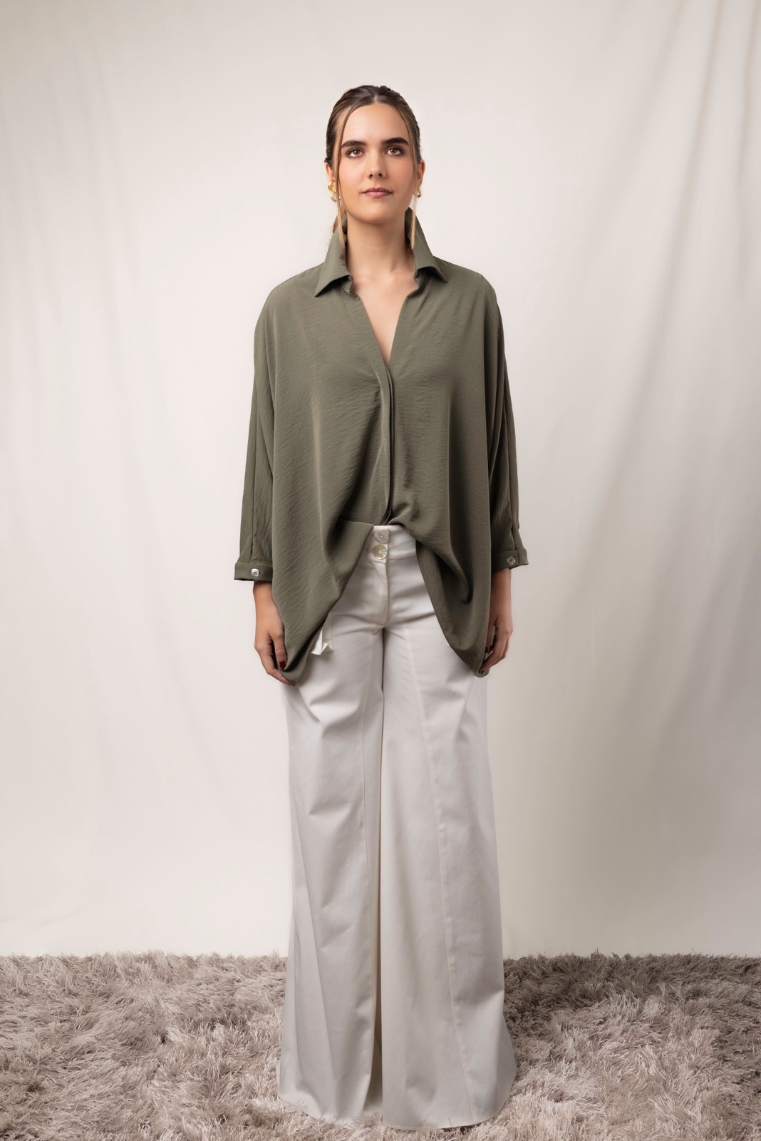 Woman wearing an oversized shirt and wide-leg trousers in a studio.